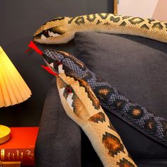 a large snake is on the arm of a couch next to a lamp and book