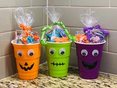 three plastic buckets with candy and candies in them on a kitchen counter top