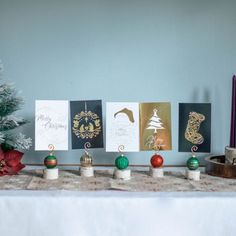 christmas cards are lined up on a table next to a small tree and other holiday decorations