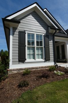 a gray house with shutters on the front and side windows is shown in this photo