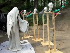 a row of wooden poles with heads on them in front of a parking lot filled with cars