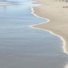 two people walking on the beach with their surfboards near the water's edge