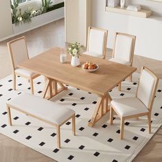 a wooden table with white chairs and a bowl of fruit on top of the table