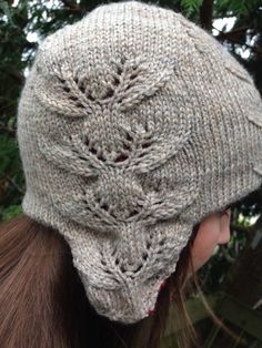 a close up of a person wearing a knitted beanie with leaves on it