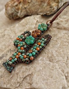 "A rustic and whimsical hand wire wrapped and beaded cactus necklace that would make a great gift for anyone who loves the desert! I wired a mixture of Czech glass beads and flowers in turquoise and rusty orange onto the cactus frame for rich color and texture.  The pendant is 2.75 \" long and hangs from an 20\" soft leather cord." Artisan Wire Wrapped Dangle Necklace, Unique Beaded Copper Jewelry, Earthy Beaded Pendant Jewelry, Bohemian Beaded Necklaces With Natural Stones And Copper, Bohemian Beaded Necklace With Natural Stones And Copper, Handmade Copper Wire Jewelry With Round Beads, Handmade Bohemian Copper Wire Jewelry, Bohemian Wire Wrapped Pendant Jewelry, Earthy Wire Wrapped Dangle Jewelry