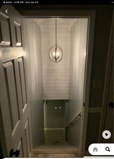 an open door leading to a bathroom with a light hanging from the ceiling above it