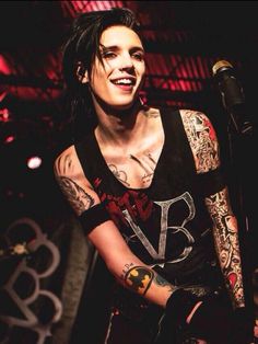 a man with tattoos and piercings on his arm holding a microphone in front of him