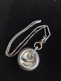 Victorian Silver Watch Case Locket Pendant, Snake Pendant with seed Pearls and Turquoise, Antique Conversion Stunning one of a kind pendant from my Twisted Vintage collection. This lovely ladies Swiss pocket watch case is rendered in .800 silver and dates to the early 1900's.  The circular case measures 1.25" and is highly decorated.  With a chased pattern runs around the edge to the front and back.  The reverse has a floral and leafy design.  Encased within the crystal is a vintage serpent coiled around a seed pearl encrusted heart with a single faux turquoise cabochon.  The watch case measures 1 1/4" across and 1 7/8" long in total. The pendant is attached to a vintage white gold filled chain measuring approximately 18.5" long.   Weighs 21 grams. The watch case is in beautiful condition, Turquoise Round Pendant Locket Jewelry, Turquoise Round Locket Jewelry, Turquoise Medallion Locket Jewelry, Round Turquoise Locket Jewelry, Turquoise Jewelry With Detachable Pendant As Gift, Heirloom Turquoise Necklace As Gift, Heirloom Turquoise Necklace For Gift, 21 Grams, Snake Pendant