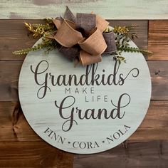 a wooden sign that says grandkids make life grand and has a bow on it