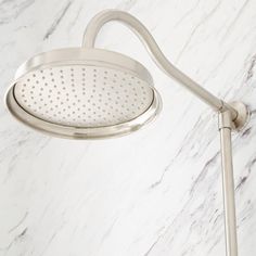 a shower head and hand shower in a white marble bathroom with stainless steel faucet