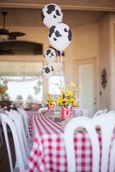 the table is set with red and white checkered cloths, balloons, and flowers