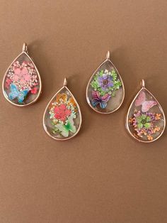 four pendants with flowers and butterflies in them on a brown surface, one is hanging from the side