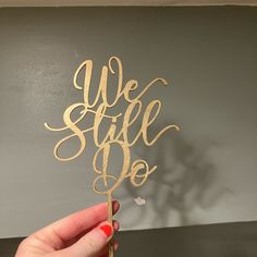 a person holding up a cake topper with the words we still do on it