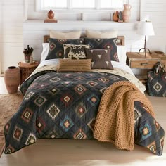 a bed in a room with pillows and blankets on top of the bedspread