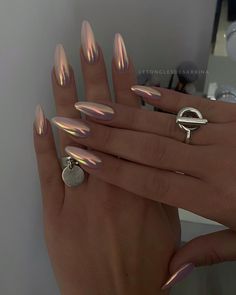 a woman's hand with shiny nail polish and rings on her fingers, in front of a mirror