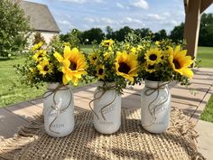 three mason jars with sunflowers tied to them