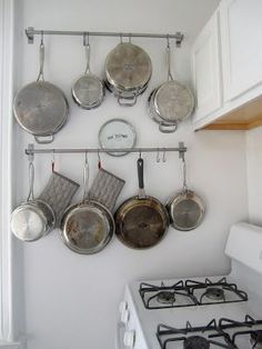 pots and pans are hanging on the wall above the stove