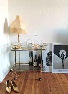 a pair of gold shoes sitting on top of a wooden floor next to a table