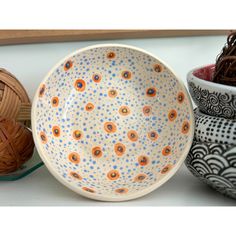 three bowls with different designs on them are sitting next to each other in front of balls of yarn