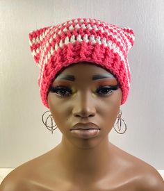 a mannequin head wearing a pink and white knitted hat with large hoop earrings