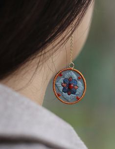 a close up of a woman's ear wearing a necklace with flowers on it