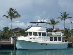 a white boat docked at a dock with palm trees in the backgrouds