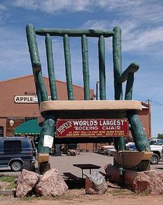 a giant chair sitting on top of a pile of rocks in front of a building