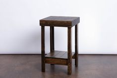 a small wooden table sitting on top of a hard wood floor next to a white wall