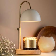 a table lamp sitting on top of a wooden stand next to a vase with flowers