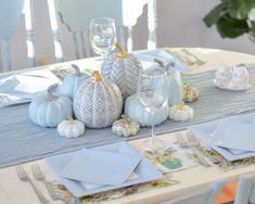 the table is set with blue and white dishes, silverware, and pumpkins