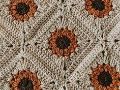 a crocheted blanket with sunflowers on the side and brown center pieces