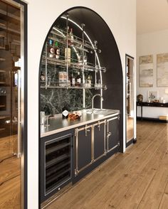 a kitchen with an arched wall and wooden floors