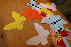 some paper flowers and butterflies on a wooden table with string attached to it's sides