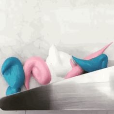 two blue and pink stuffed animals laying on top of a metal table next to each other