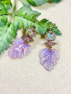 Gorgeous leaves with gold etching made by Neli Da.  Topped with lavender and gold spacer, beautiful lampwork beads by Laura Walters and little ametyst beads. Handmade Purple Earrings For Festive Occasions, Festive Handmade Purple Earrings, Gold Spiritual Beaded Earrings For Gifts, Artisan Purple Round Bead Earrings, Artisan Purple Round Beaded Earrings, Gold Jewelry Bead Caps For Crafting, Gold Bead Caps Jewelry For Crafting, Handmade Gold Beaded Earrings With Czech Glass, Bohemian Gold Earrings With Bead Caps