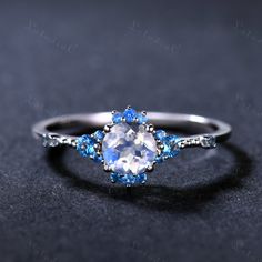 an oval shaped blue and white diamond ring on a black surface with diamonds around it