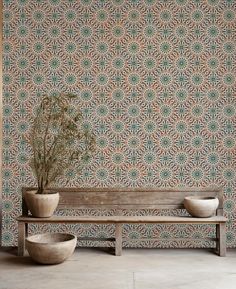 a wooden bench sitting in front of a wall with a plant on top of it