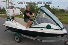 a man sitting on the back of a white and green speed boat with an open cockpit