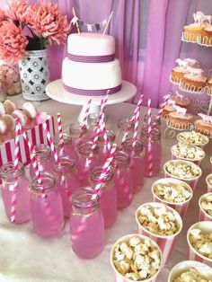 a table topped with lots of pink and white desserts next to cupcakes