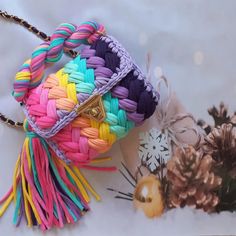 a multicolored handbag sitting on top of a table next to pine cones