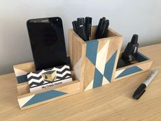 a cell phone and pen holder sitting on a wooden desk next to a smart phone