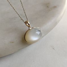 ITEM DESCRIPTION: >>The pendant is made from Solid 14K Yellow Gold. Gemstone used is absolutely natural and ethically sourced.  >>Natural White Moonstones cabochon with bezel setting are studded on it with utmost precision.  >>This is a minimalist design and is absolutely hassle-free and everyday jewelry.  ✓ Gem: White Moonstone ✓ Gem size: 14x19 mm oval ✓ Gem weight: 17.18 carats ✓ Gold purity: 14K (58.33% approx.) ✓ Gold weight: 0.58 grams  ✓ Gross weight: 4.02 grams The Gold purity is guaranteed and it comes with authentic 14K gold hallmark. Since these Pendants are handmade, they are Nickel/Lead FREE.  CUSTOMIZATION: --> You can choose your own gemstone as well. --> Main Gemstone can be substituted with the gem of your choice. --> Kindly drop a message for the same. CUSTOMER SUPPORT: - Moonstone Jewelry Set, Luxury Si Clarity Moonstone Jewelry, Elegant Yellow Gold Moonstone Ring With Large Stone, White Polished Finish Round Pendant Jewelry, Gold Polished Moonstone Jewelry, Gold Moonstone Jewelry With Polished Finish, Timeless White Gemstone Jewelry, Timeless White Gemstone Necklace, White Oval Pendant With Polished Finish