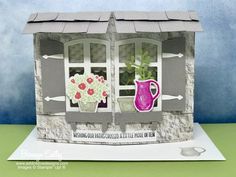 a paper house with flowers in the window