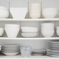 white dishes and bowls are stacked on shelves