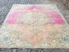 a pink and blue rug sitting on top of a cobblestone road