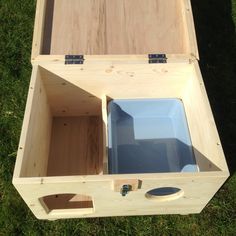 an open wooden box on the grass with two blue containers in it's lid