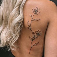 a woman's back tattoo with flowers on her left shoulder and the upper part of her body