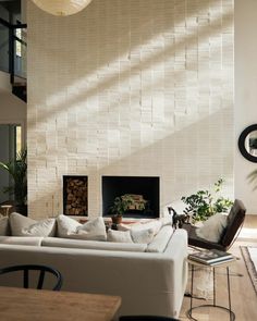 a living room filled with furniture and a fire place in front of a white brick wall