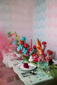 a long table is set with colorful flowers and candles for a festive dinner party