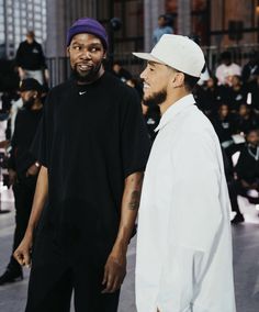 two young men standing next to each other in front of a large group of people